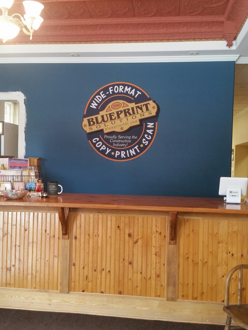 Blueprint Solutions logo sign on a navy wall behind the front counter